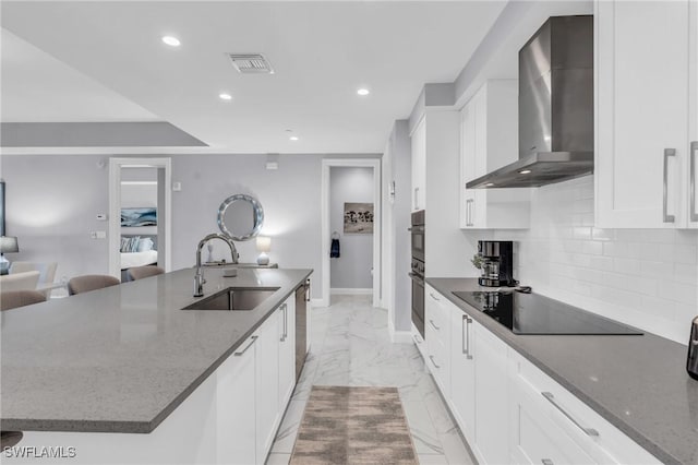 kitchen featuring a large island, sink, wall chimney exhaust hood, dark stone counters, and black appliances