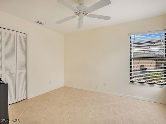 unfurnished bedroom with light tile patterned floors, a closet, and ceiling fan