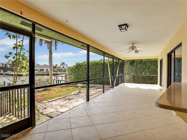 unfurnished sunroom with a water view and ceiling fan