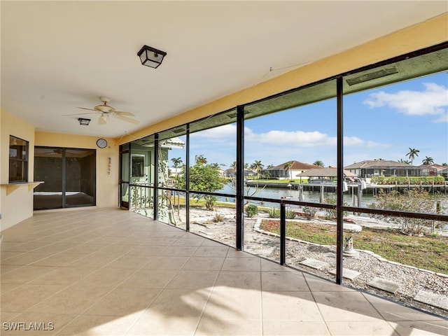 unfurnished sunroom with a water view and ceiling fan