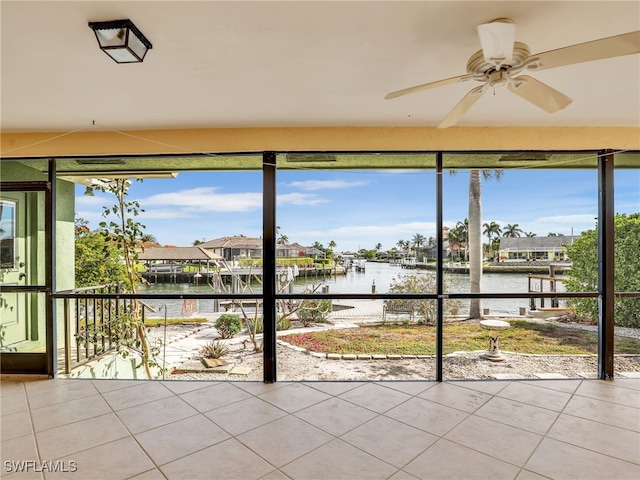 unfurnished sunroom featuring a water view, ceiling fan, and a healthy amount of sunlight