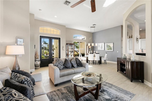 living room with french doors, light hardwood / wood-style flooring, ceiling fan, and a high ceiling