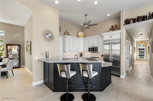 kitchen featuring light stone counters, white cabinetry, appliances with stainless steel finishes, and tasteful backsplash