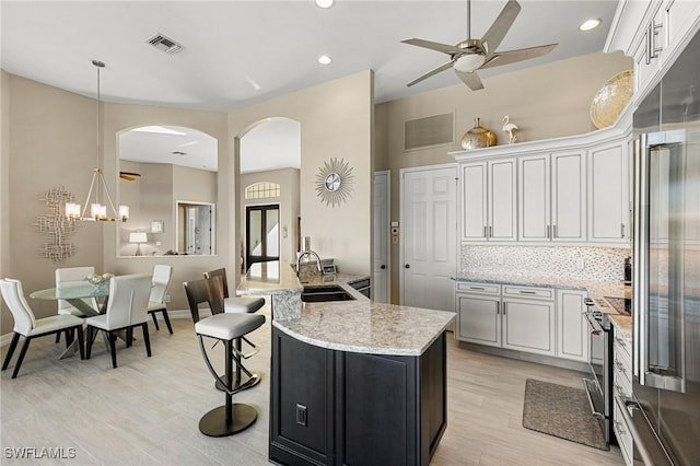 kitchen featuring decorative backsplash, appliances with stainless steel finishes, sink, decorative light fixtures, and white cabinets