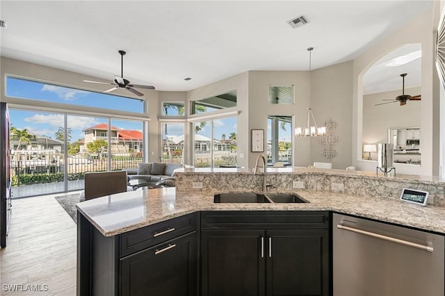 kitchen with dishwasher, light stone counters, sink, and ceiling fan with notable chandelier