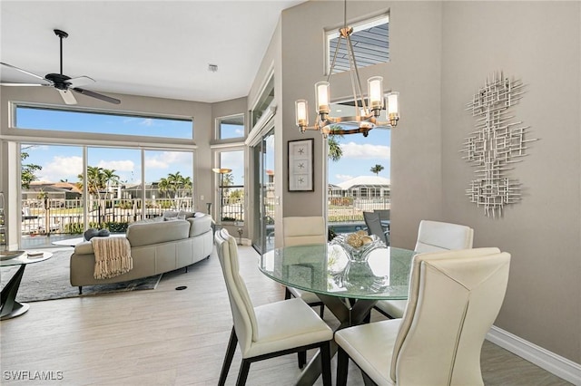 dining area with wood-type flooring and ceiling fan with notable chandelier