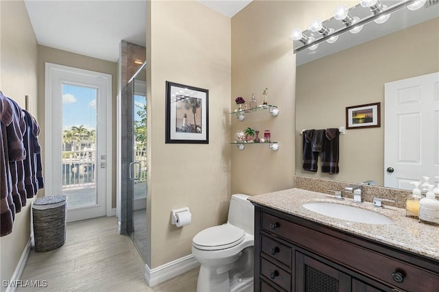 bathroom featuring hardwood / wood-style flooring, vanity, a shower with shower door, and toilet