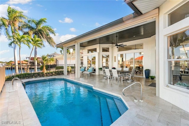 view of pool with ceiling fan, a patio area, and a water view