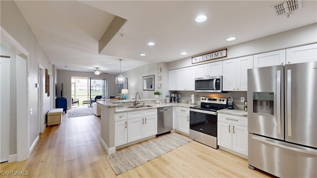 kitchen with sink, kitchen peninsula, ceiling fan, white cabinetry, and stainless steel appliances