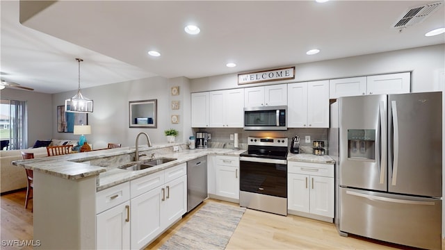 kitchen with kitchen peninsula, white cabinetry, sink, and appliances with stainless steel finishes