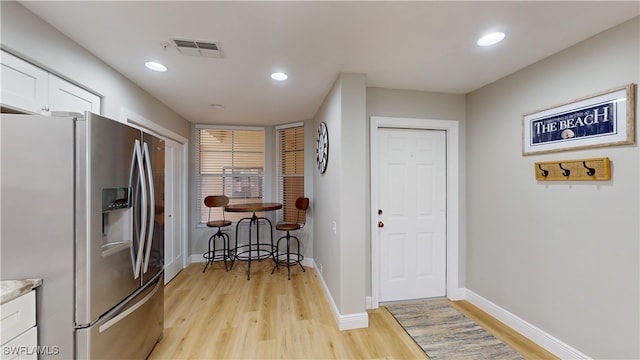 interior space with white cabinetry, stainless steel fridge with ice dispenser, and light hardwood / wood-style flooring