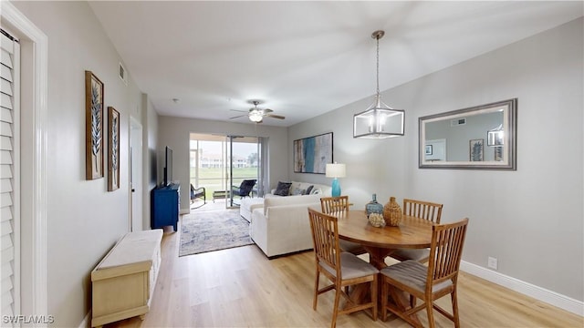 dining room with ceiling fan with notable chandelier and light wood-type flooring