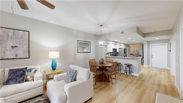 living room with ceiling fan and light hardwood / wood-style flooring