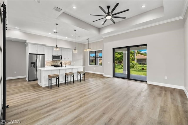 kitchen featuring appliances with stainless steel finishes, a tray ceiling, white cabinetry, and hanging light fixtures