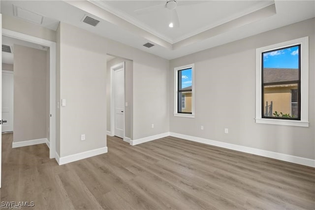 spare room featuring light hardwood / wood-style flooring, a raised ceiling, plenty of natural light, and ceiling fan