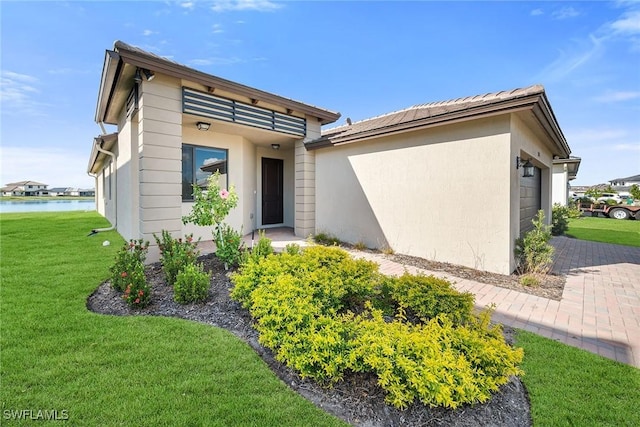 view of front of house featuring a water view, a garage, and a front lawn