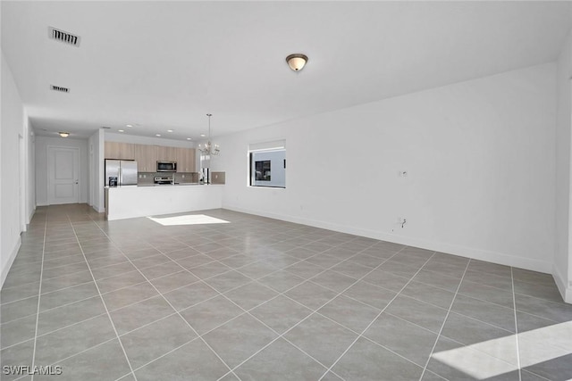 unfurnished living room featuring a chandelier and light tile patterned flooring