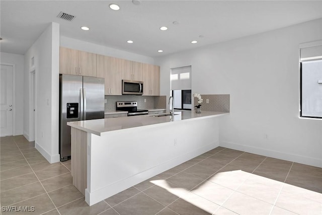 kitchen featuring light tile patterned flooring, sink, kitchen peninsula, and stainless steel appliances