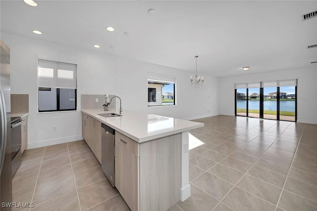 kitchen with kitchen peninsula, tasteful backsplash, sink, a water view, and dishwasher