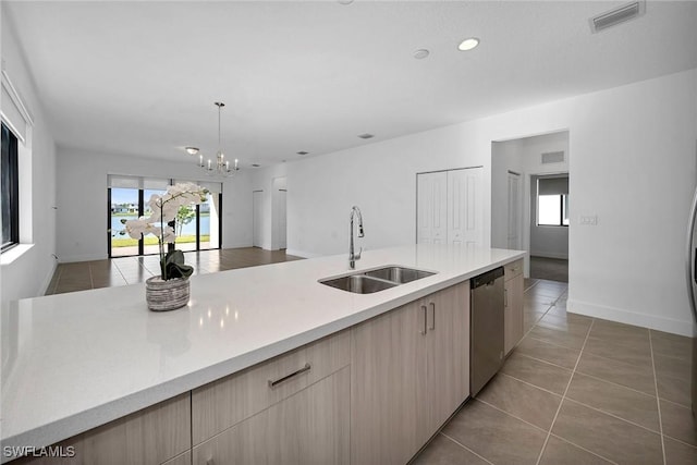 kitchen featuring sink, hanging light fixtures, stainless steel dishwasher, light brown cabinetry, and light tile patterned flooring