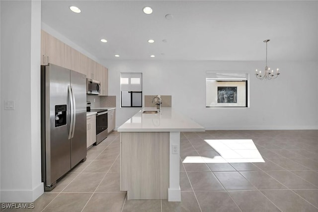 kitchen featuring sink, hanging light fixtures, appliances with stainless steel finishes, light tile patterned flooring, and a chandelier