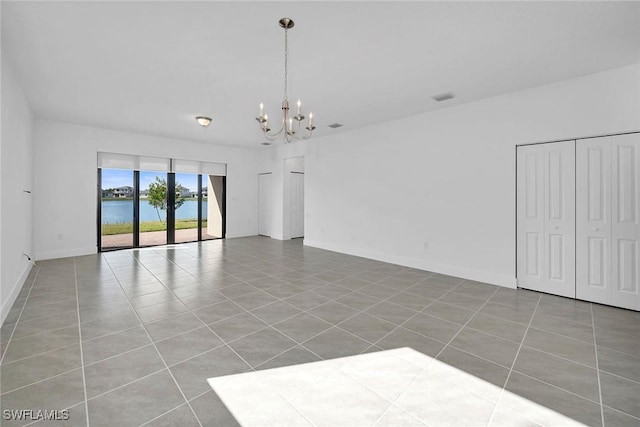 tiled empty room with a water view and a chandelier