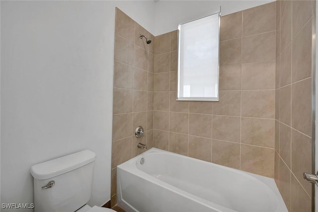 bathroom featuring tiled shower / bath combo and toilet