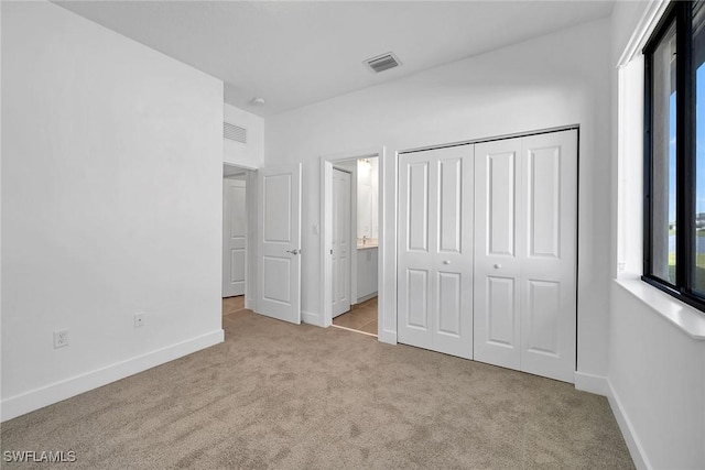 unfurnished bedroom with a closet and light colored carpet