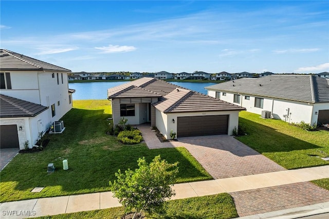 ranch-style home with cooling unit, a garage, a water view, and a front lawn