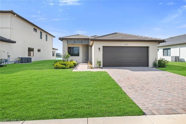 view of front of property featuring a garage, a front lawn, and central air condition unit