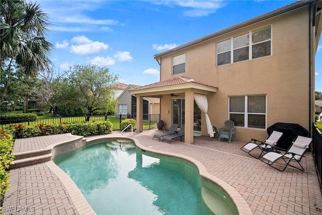 rear view of house with a fenced in pool, a patio area, and ceiling fan