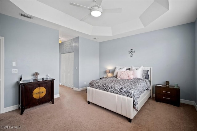 carpeted bedroom featuring a tray ceiling and ceiling fan