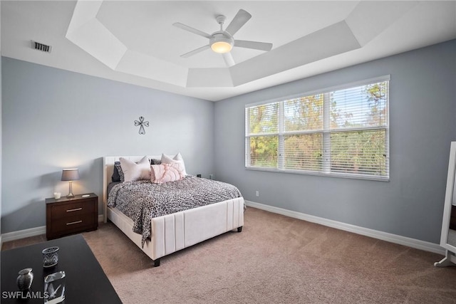 carpeted bedroom with a tray ceiling and ceiling fan