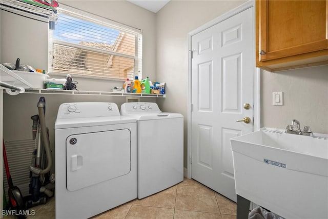 clothes washing area with separate washer and dryer, sink, light tile patterned flooring, and cabinets