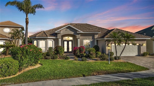 mediterranean / spanish-style home with a garage, a yard, and french doors