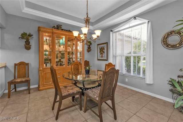 tiled dining room featuring a tray ceiling, ornamental molding, and an inviting chandelier