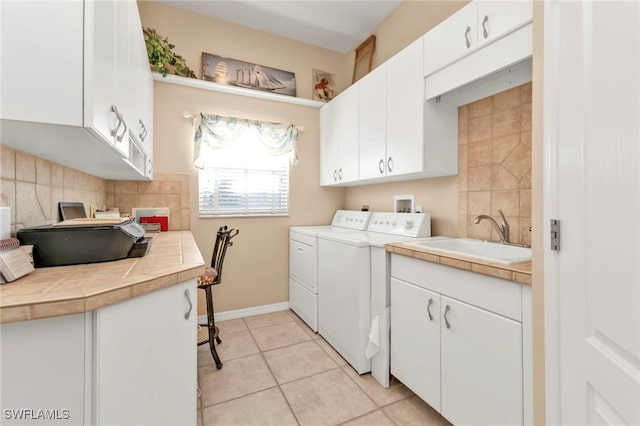 laundry area with cabinets, sink, separate washer and dryer, and light tile patterned flooring