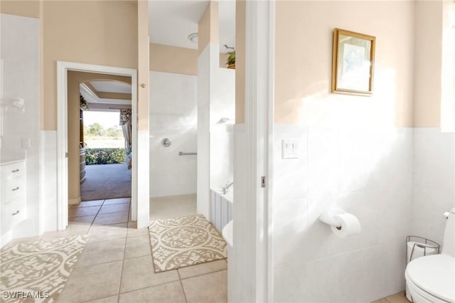 bathroom with tile patterned flooring, tile walls, and toilet