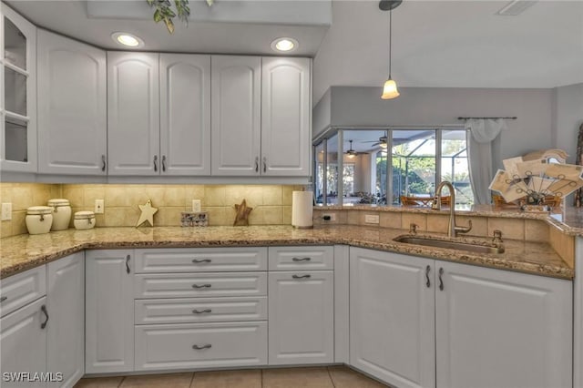 kitchen featuring light stone counters, white cabinetry, and sink