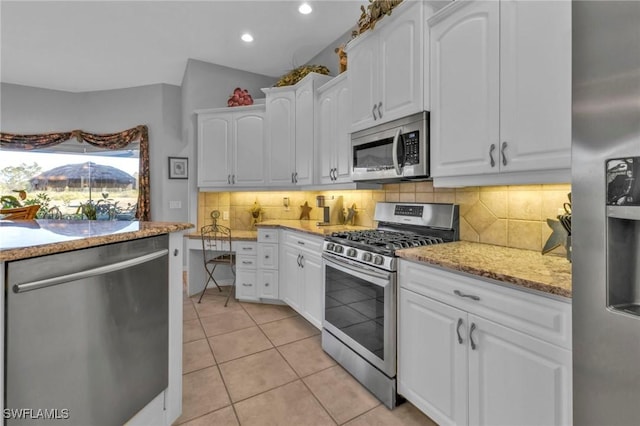 kitchen featuring white cabinets, light stone countertops, light tile patterned floors, and stainless steel appliances