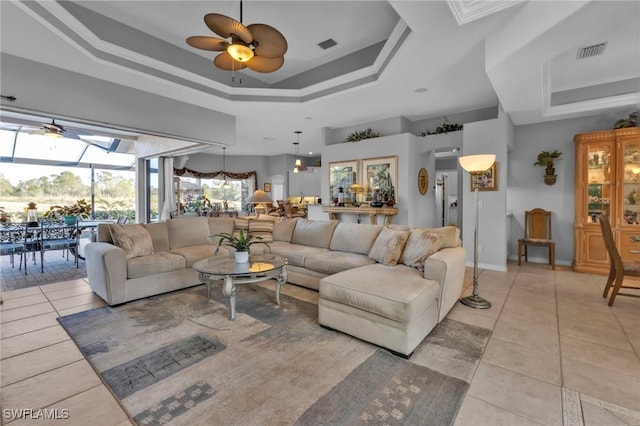 living room featuring light tile patterned floors, a raised ceiling, ceiling fan, and a high ceiling