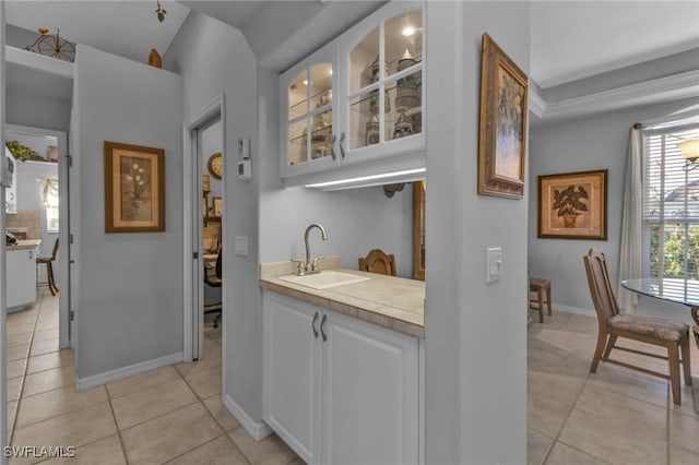 bar with sink, white cabinets, and light tile patterned flooring