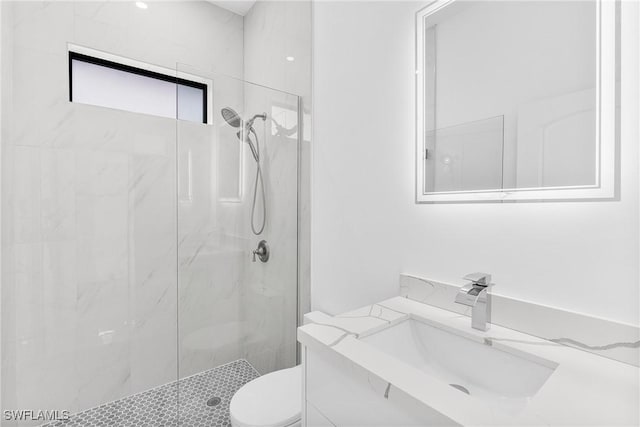 bathroom with vanity, toilet, and a tile shower