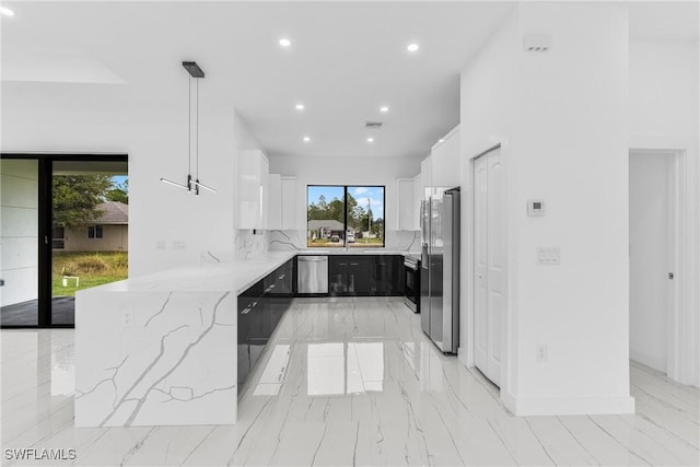 kitchen featuring hanging light fixtures, light stone counters, decorative backsplash, white cabinets, and appliances with stainless steel finishes