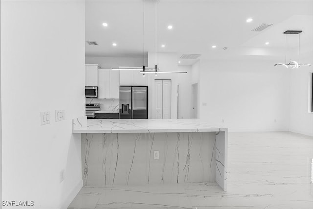 kitchen featuring pendant lighting, kitchen peninsula, appliances with stainless steel finishes, light stone counters, and white cabinetry