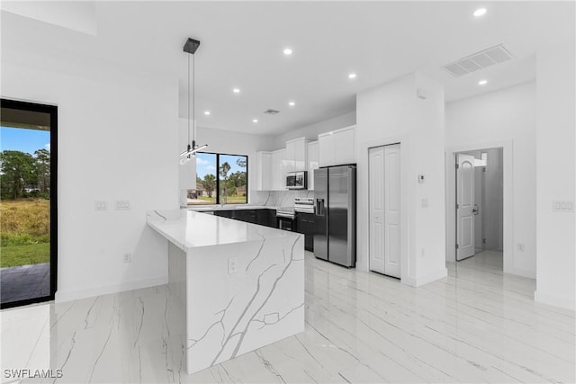 kitchen featuring pendant lighting, white cabinets, appliances with stainless steel finishes, tasteful backsplash, and kitchen peninsula