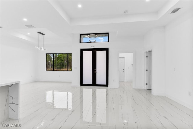 entryway featuring a towering ceiling and a raised ceiling