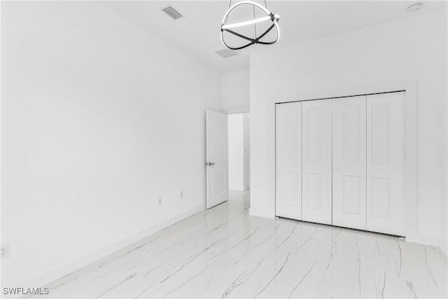 unfurnished bedroom with an inviting chandelier and a closet