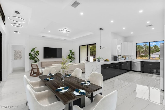 dining space with a chandelier, a raised ceiling, and french doors