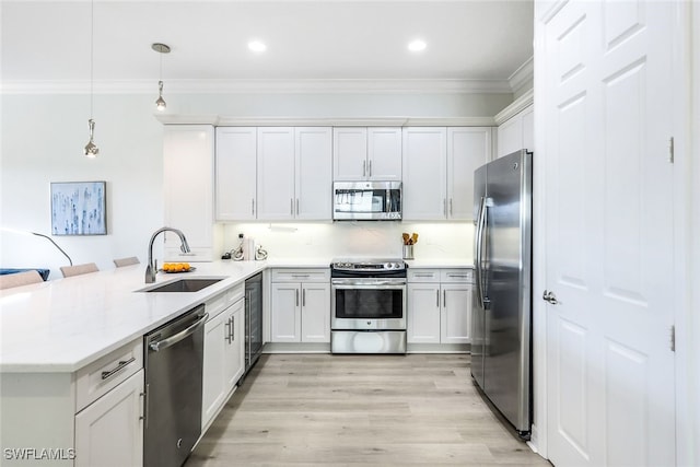 kitchen featuring kitchen peninsula, stainless steel appliances, sink, decorative light fixtures, and white cabinets